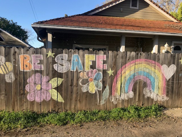 Fence with chalk drawing saying be safe